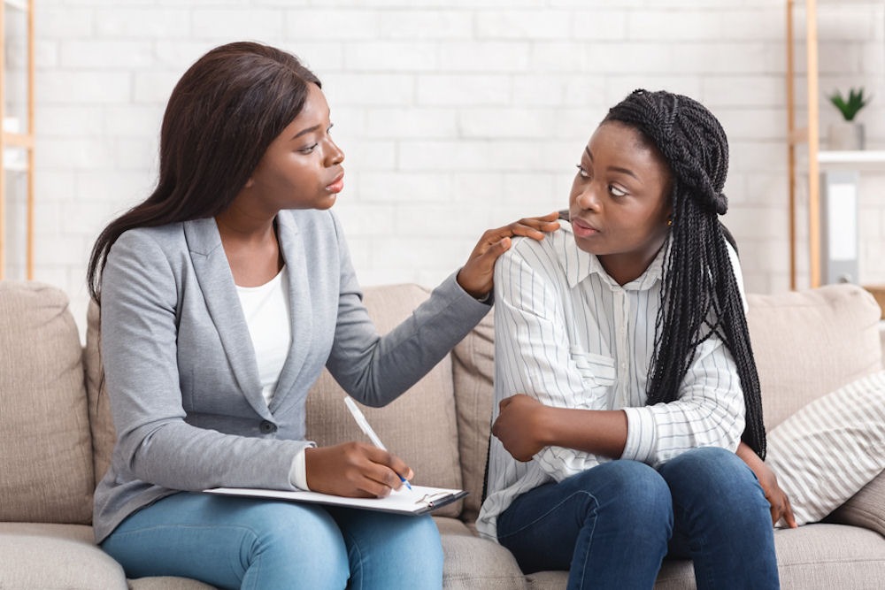 Therapist reassures young woman with box braids