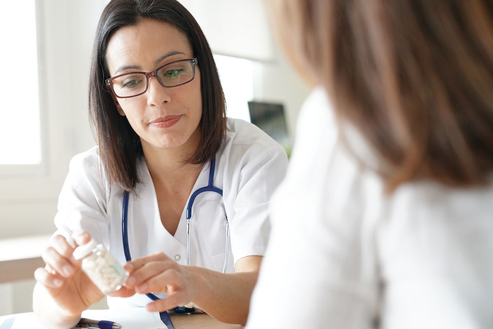 Young doctor smiling and holding clipboard describing Xanax detox.