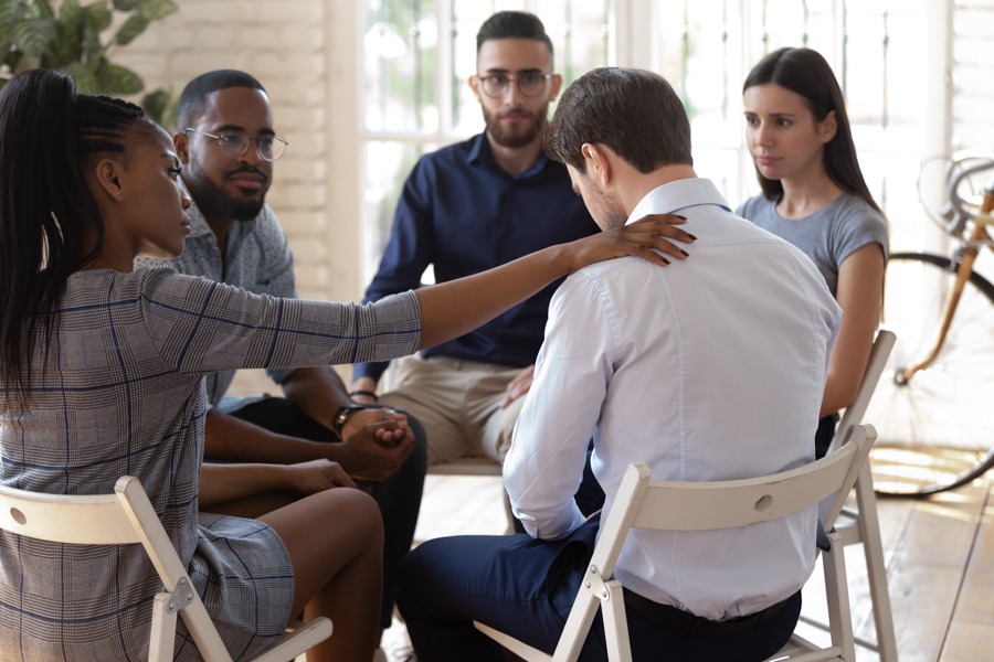 Support group comforting a member who is struggling with worries about social interactions